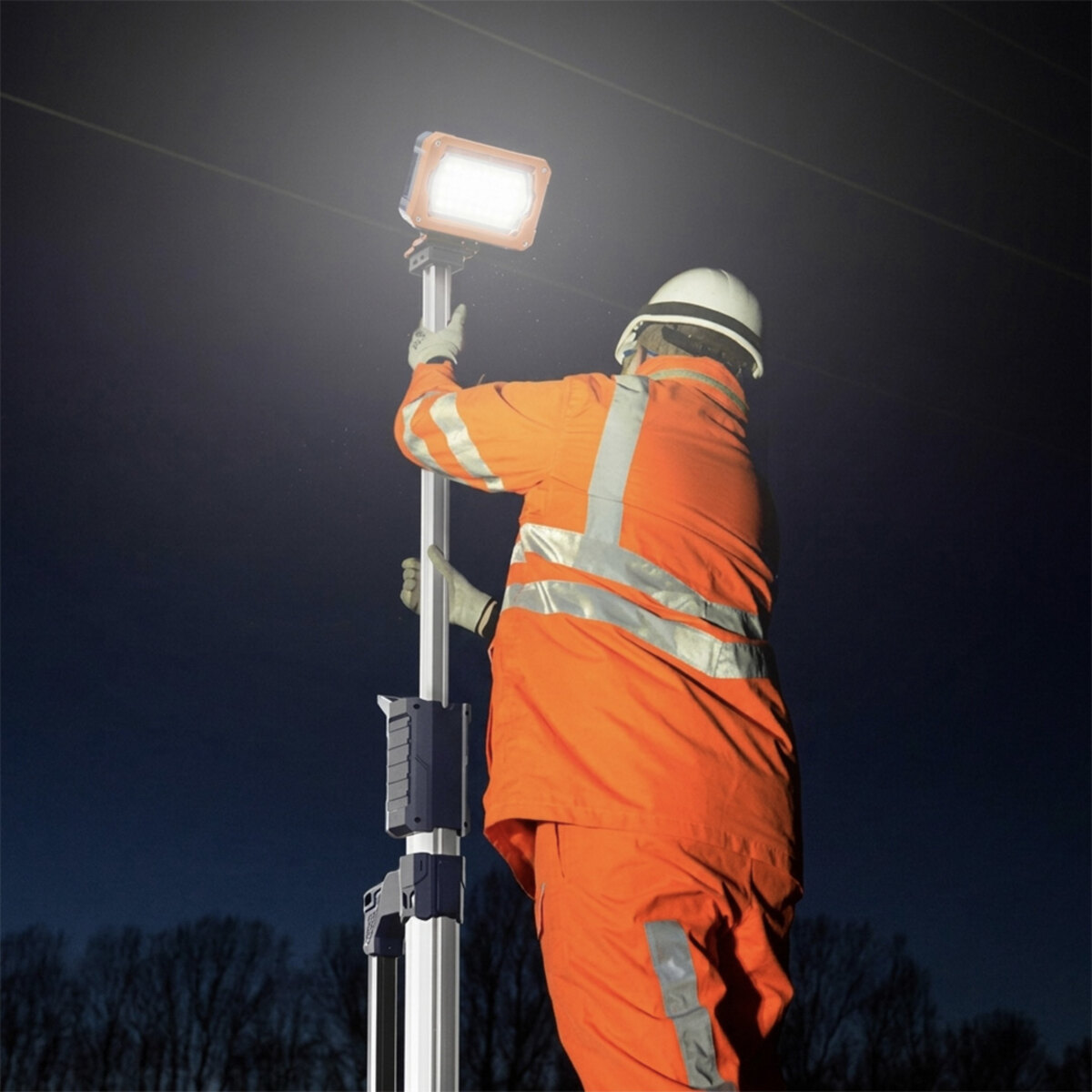 Operator raising the mast of a G-COMIN light tower at night