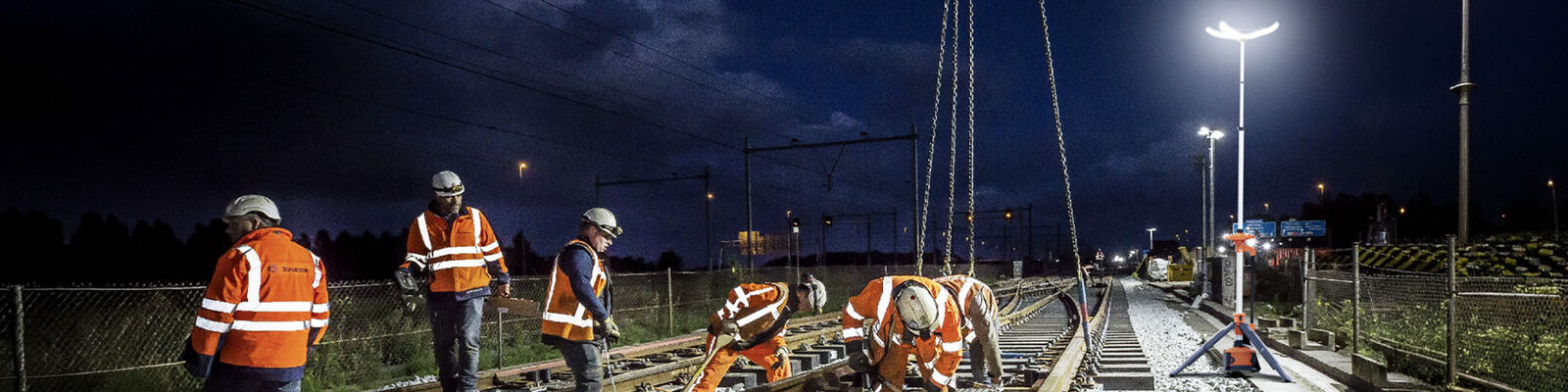 Cuadrilla ferroviaria trabajando de noche bajo la luz de una PL-300