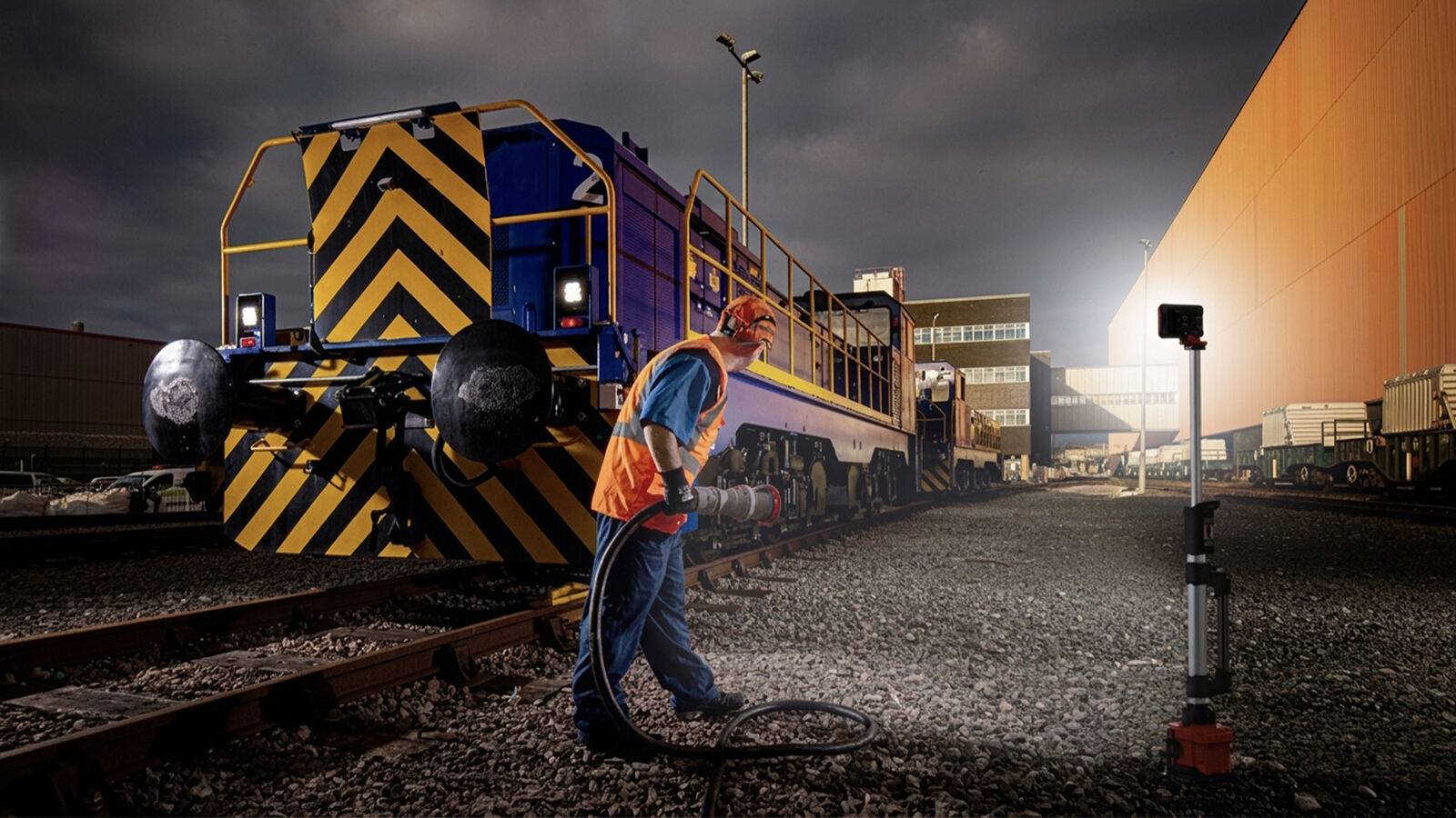 Trabajador junto a una locomotora con una TL-100 iluminando el patio de maniobras