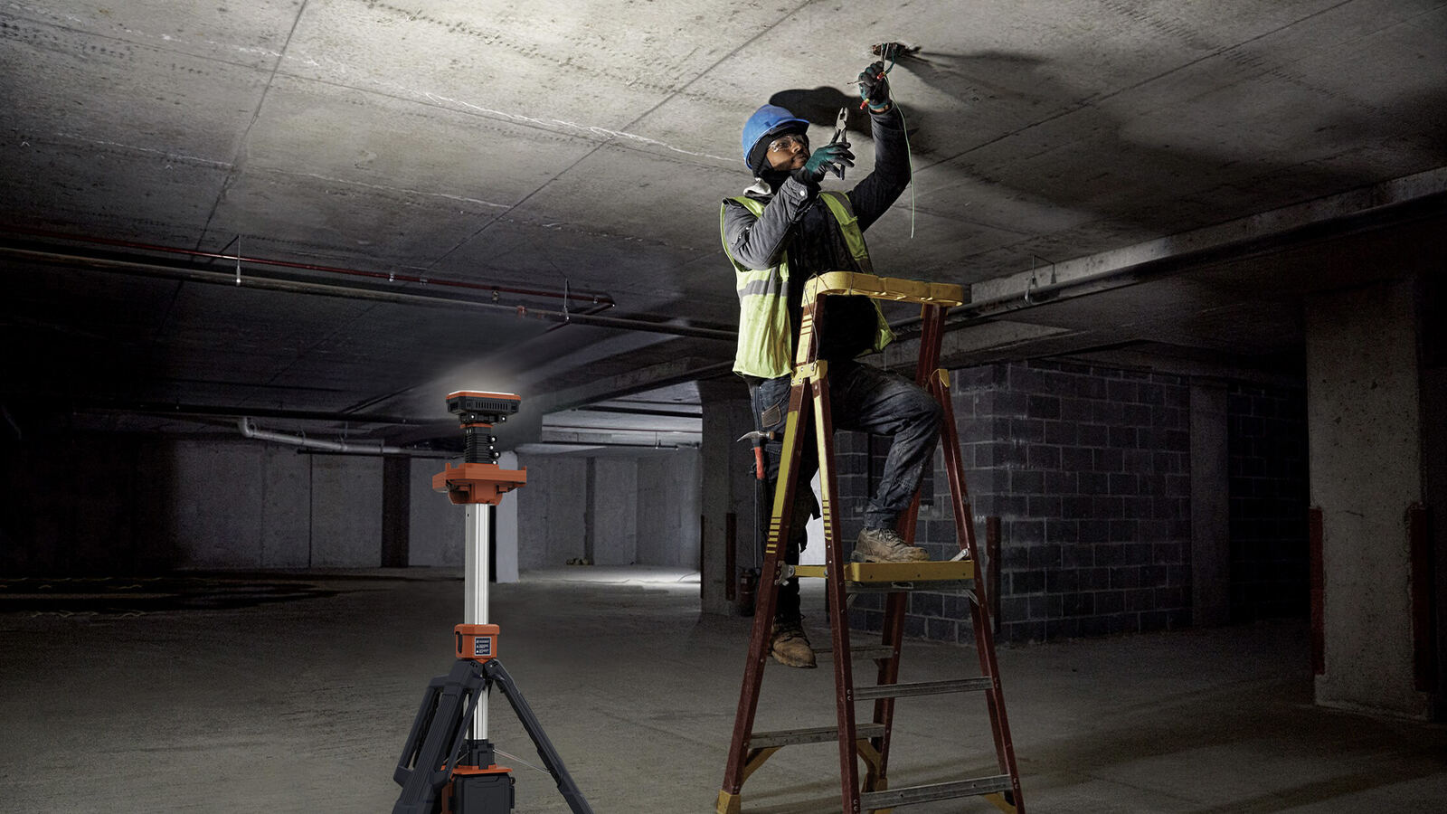 Electricista en una escalera trabajando en el techo de un estacionamiento iluminado por una TL-200